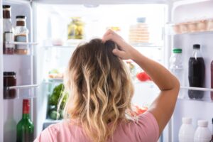 Rear,view,of,a,confused,woman,looking,in,open,refrigerator